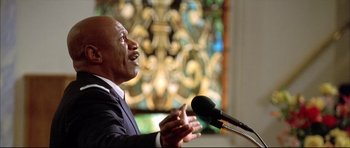 Movie still from “Dark Blue” (2002), directed by Ron Shelton – A man in a suit is speaking into a microphone; Close Up shot, Low angle