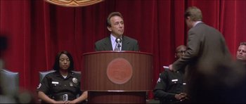 Movie still from “Dark Blue” (2002), directed by Ron Shelton – A man standing at a podium speaking to a crowd of onlookers; Medium shot, Low angle
