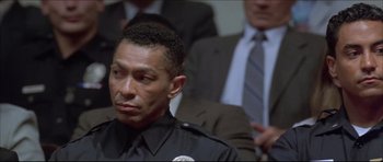 Movie still from “Dark Blue” (2002), directed by Ron Shelton – A man in a police uniform sitting in front of other men; Close Up shot, Low angle