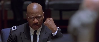 Movie still from “Dark Blue” (2002), directed by Ron Shelton – A man in a suit and tie holding his hand up to his ear; Close Up shot, Low angle