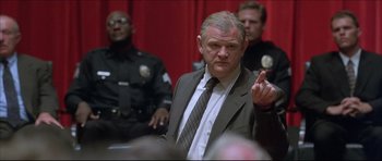 Movie still from “Dark Blue” (2002), directed by Ron Shelton – A man in a suit and tie in front of a group of police officers; Close Up shot, Low angle