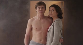 A man and a woman standing next to each other in front of a bathroom mirror