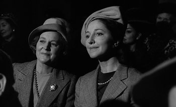 Movie still from “Darling” (1965), directed by John Schlesinger – A couple of women wearing hats in a dark room; Close Up shot, Low angle