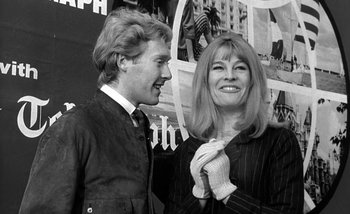 Movie still from “Darling” (1965), directed by John Schlesinger – A man standing next to a woman in a black and white photo; Medium shot, Low angle