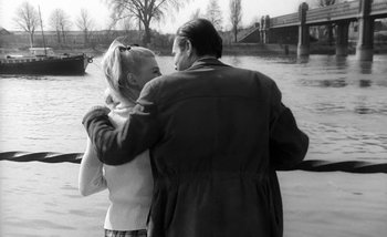 Movie still from “Darling” (1965), directed by John Schlesinger – A man and a woman hugging near a body of water; Medium shot, Over the shoulder angle