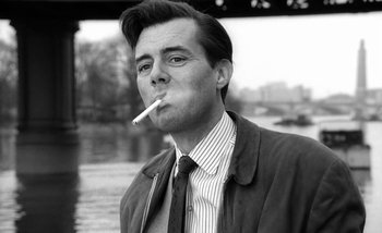 Movie still from “Darling” (1965), directed by John Schlesinger – A black and white photo of a man smoking a cigarette; Close Up shot, Low angle