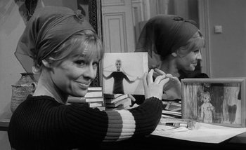 Movie still from “Darling” (1965), directed by John Schlesinger – A black and white photo of a woman sitting at a table; Medium shot, Over the shoulder angle