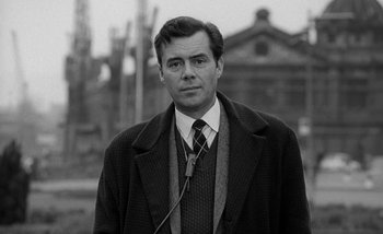 Movie still from “Darling” (1965), directed by John Schlesinger – A black and white photo of a man wearing a suit and tie; Close Up shot, Low angle