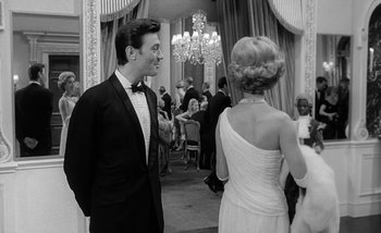 Movie still from “Darling” (1965), directed by John Schlesinger – A man and a woman in formal wear at a formal event; Medium shot, Over the shoulder angle