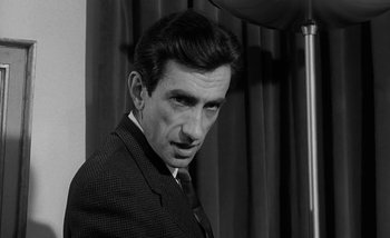 Movie still from “Darling” (1965), directed by John Schlesinger – Black and white photograph of a man wearing a suit and tie; Close Up shot, High angle