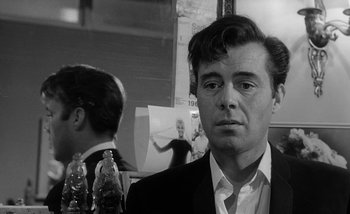 Movie still from “Darling” (1965), directed by John Schlesinger – Black and white photograph of a man in a suit; Close Up shot, Over the shoulder angle