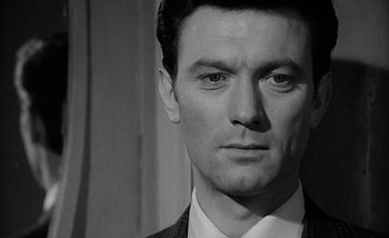 Movie still from “Darling” (1965), directed by John Schlesinger – Black and white photograph of a man in a suit; Close Up shot, Over the shoulder angle