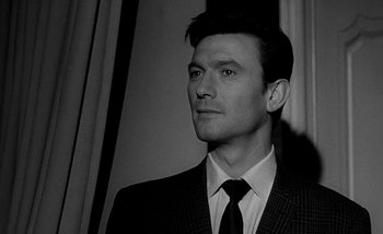 Movie still from “Darling” (1965), directed by John Schlesinger – Black and white photograph of a man wearing a suit and tie; Close Up shot, Low angle
