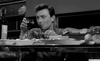 Movie still from “Darling” (1965), directed by John Schlesinger – A man sitting at a table with a glass of red wine; Close Up shot, Low angle