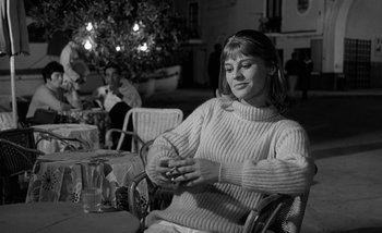 Movie still from “Darling” (1965), directed by John Schlesinger – A black and white photo of a woman sitting at a table; Medium shot, Low angle