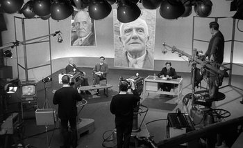 Movie still from “Darling” (1965), directed by John Schlesinger – A group of people sitting in front of a large picture; Wide shot, High angle