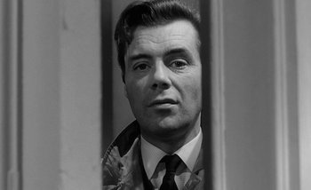 Movie still from “Darling” (1965), directed by John Schlesinger – Black and white photograph of a man in a suit and tie; Close Up shot, Low angle