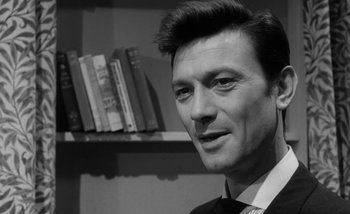 Movie still from “Darling” (1965), directed by John Schlesinger – Black and white photograph of a man in front of a book shelf; Close Up shot, Over the shoulder angle