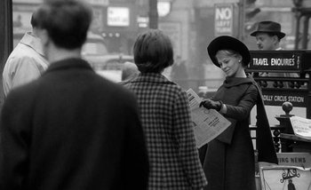 Movie still from “Darling” (1965), directed by John Schlesinger – A woman in a black hat is holding a newspaper; Medium shot, Over the shoulder angle