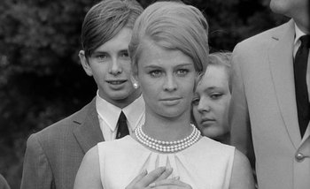 Movie still from “Darling” (1965), directed by John Schlesinger – A woman in a white dress with two men in a black suit; Close Up shot, Low angle
