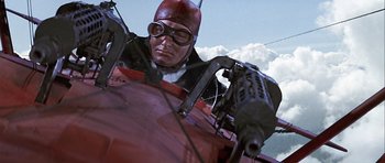 Movie still from “Darling Lili” (1970), directed by Blake Edwards – A man wearing a helmet and goggles is in an airplane; Medium shot, Low angle