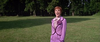 Movie still from “Darling Lili” (1970), directed by Blake Edwards – A woman in a purple suit standing in the grass; Medium shot, Low angle