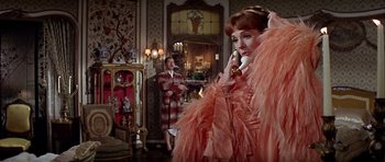 Movie still from “Darling Lili” (1970), directed by Blake Edwards – A woman talking on a phone while a man stands next to her; Medium shot, Over the shoulder angle