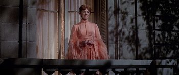 Movie still from “Darling Lili” (1970), directed by Blake Edwards – A woman in a pink dress standing in front of a window; Medium shot, Low angle