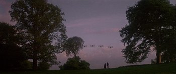 Movie still from “Darling Lili” (1970), directed by Blake Edwards – Two people are standing on a hill looking up at airplanes flying in the sky; Extreme Wide shot, Low angle