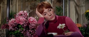 Movie still from “Darling Lili” (1970), directed by Blake Edwards – A woman sitting in front of a table with a vase of flowers; Close Up shot, High angle