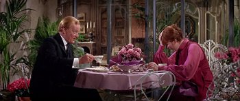 Movie still from “Darling Lili” (1970), directed by Blake Edwards – A man and a woman sitting at a table with a plate of food; Medium shot, Over the shoulder angle