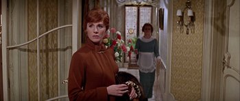 Movie still from “Darling Lili” (1970), directed by Blake Edwards – A woman in a brown coat holding an umbrella in front of another woman in a brown dress; Medium shot, Low angle