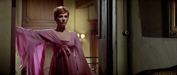 Movie still from “Darling Lili” (1970), directed by Blake Edwards – A woman in a pink dress standing next to a door; Medium shot, Low angle