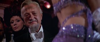 Movie still from “Darling Lili” (1970), directed by Blake Edwards – An older man in a tuxedo looking at a woman in a purple dress; Close Up shot, Over the shoulder angle