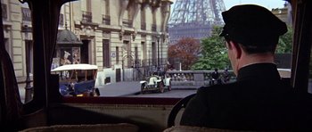 Movie still from “Darling Lili” (1970), directed by Blake Edwards – An old car is parked on the side of the street; Medium shot, Over the shoulder angle