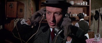 Movie still from “Darling Lili” (1970), directed by Blake Edwards – A man in a suit and hat is talking on a phone; Close Up shot, Low angle