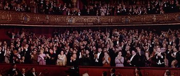 Movie still from “Darling Lili” (1970), directed by Blake Edwards – A large group of people in formal wear clapping in a theater; Extreme Wide shot, High angle