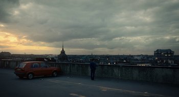 A man standing on a ledge looking over a city