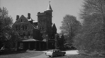 Movie still from “David and Lisa” (1962), directed by Frank Perry – An old photo of an old building with a car parked in front of it; Extreme Wide shot, Low angle