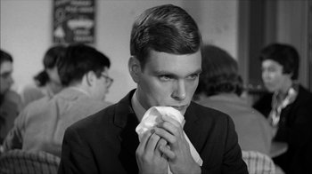 Movie still from “David and Lisa” (1962), directed by Frank Perry – A man in a black suit holding a napkin to his mouth; Close Up shot, Over the shoulder angle