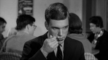Movie still from “David and Lisa” (1962), directed by Frank Perry – A man in a suit and tie is eating something; Close Up shot, Over the shoulder angle