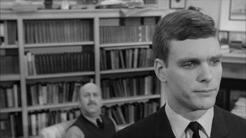 Movie still from “David and Lisa” (1962), directed by Frank Perry – A man in a suit standing next to another man in a library; Close Up shot, Over the shoulder angle