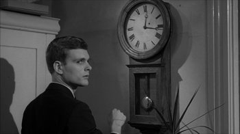Movie still from “David and Lisa” (1962), directed by Frank Perry – A man standing in front of an old clock; Close Up shot, Low angle