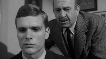 Movie still from “David and Lisa” (1962), directed by Frank Perry – A man standing next to another man in a suit; Close Up shot, Over the shoulder angle