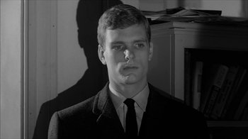Movie still from “David and Lisa” (1962), directed by Frank Perry – A man in a suit and tie in front of a cabinet; Close Up shot, Low angle