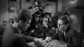 Movie still from “David and Lisa” (1962), directed by Frank Perry – Two men are playing a game of chess in front of a crowd; Medium shot, High angle