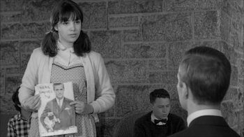 Movie still from “David and Lisa” (1962), directed by Frank Perry – A woman holding a picture of a man in front of two other men; Medium shot, Over the shoulder angle