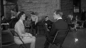 Movie still from “David and Lisa” (1962), directed by Frank Perry – A group of people sitting in chairs in front of a brick wall; Medium shot, Over the shoulder angle