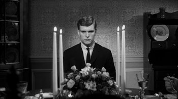 Movie still from “David and Lisa” (1962), directed by Frank Perry – A man in a suit sitting in front of candles; Medium shot, High angle
