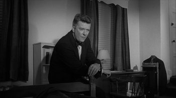 Movie still from “David and Lisa” (1962), directed by Frank Perry – A man sitting at a desk in a room; Medium shot, Low angle